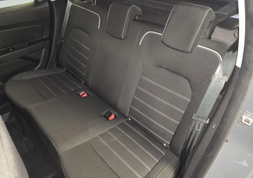 Vue arrière côté droit sur la banquette noire avec surpiqûres blanches du Dacia Duster 2024 gris urbain.