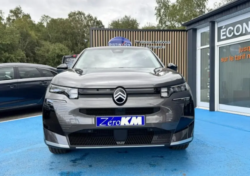 Vue frontale d'un Citroën C5 Aircross gris Platinium avec calandre moderne et logo centré sur un parking bleu.