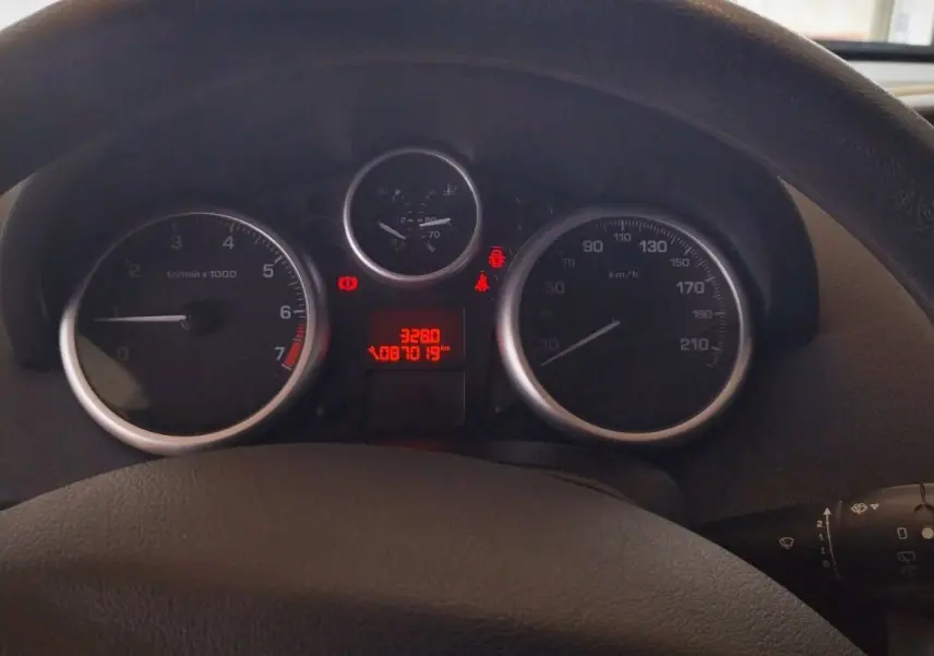 Vue rapprochée du tableau de bord et du volant noir d'une Peugeot 207+ 1.4l HDi 2013 avec compteurs analogiques.