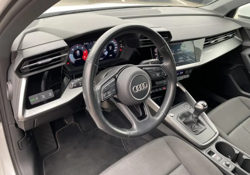 Intérieur de l'Audi A3 Sportback 2022 vu côté conducteur, volant cuir noir et tableau de bord digital.