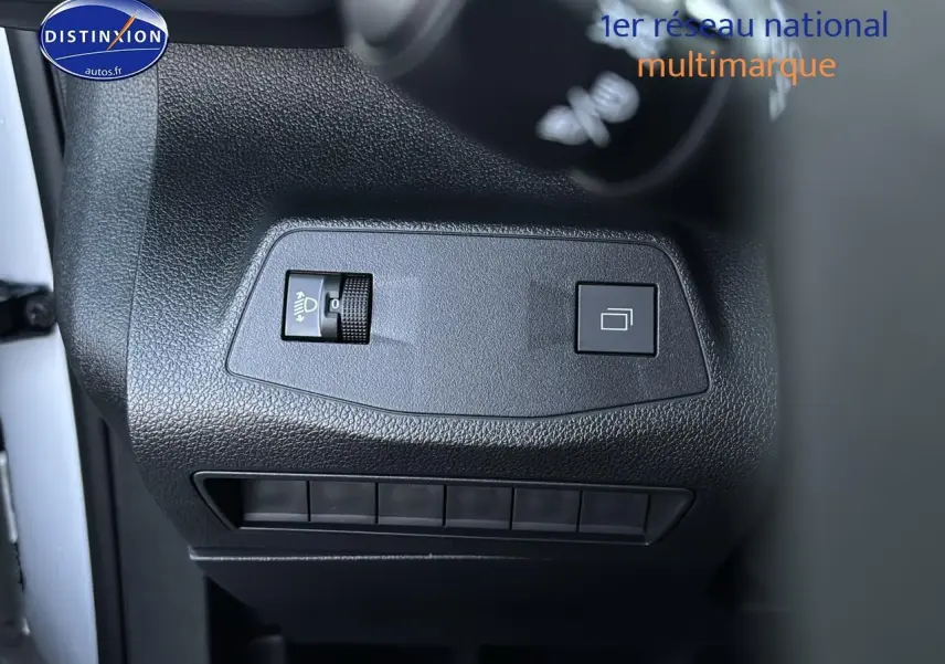 Détail des commandes de réglage des phares et du tableau de bord du Citroën Berlingo Fourgon blanc, vue intérieure côté gauche.