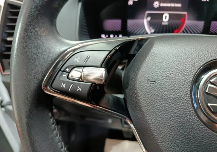 Gros plan sur le volant cuir noir du Skoda Karoq 2024, avec commandes audio et écran digital en arrière-plan.