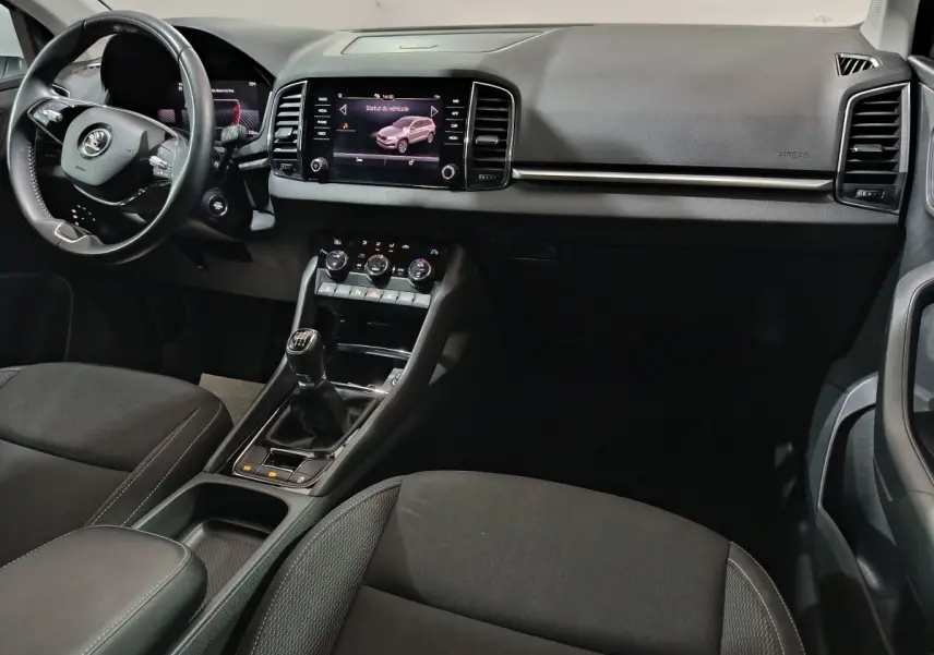 Intérieur noir du Skoda Karoq 2024, vue de face côté conducteur avec tableau de bord et écran tactile central.
