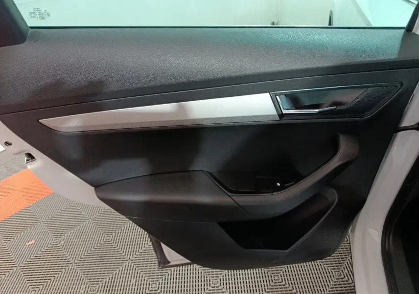 Vue rapprochée de la porte intérieure côté gauche blanche du Skoda Karoq 2024 avec poignée et insert argenté.