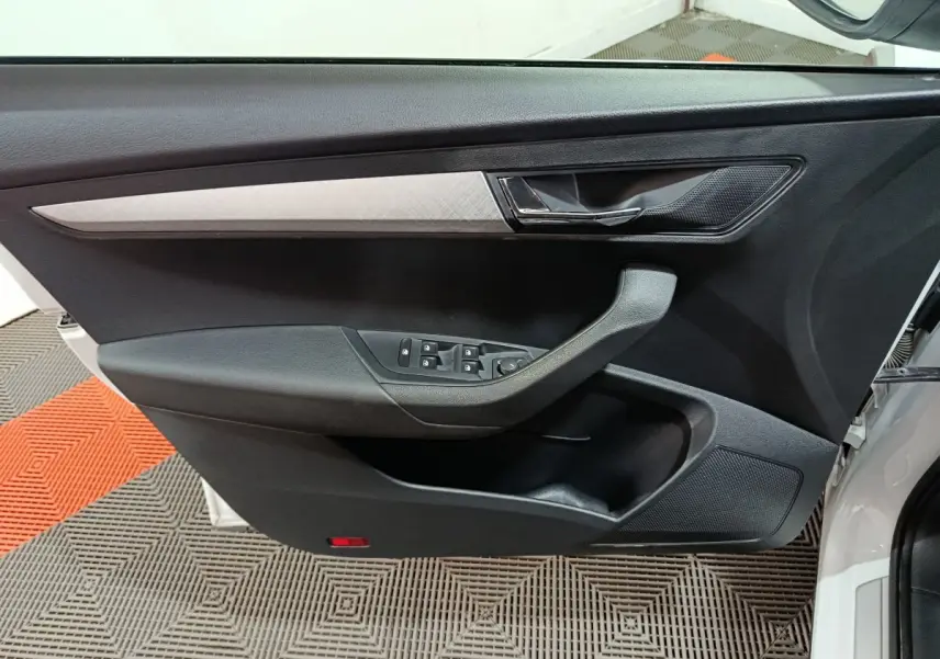 Vue intérieure sur la porte avant gauche noire avec insert argenté du Skoda Karoq blanc 2024.