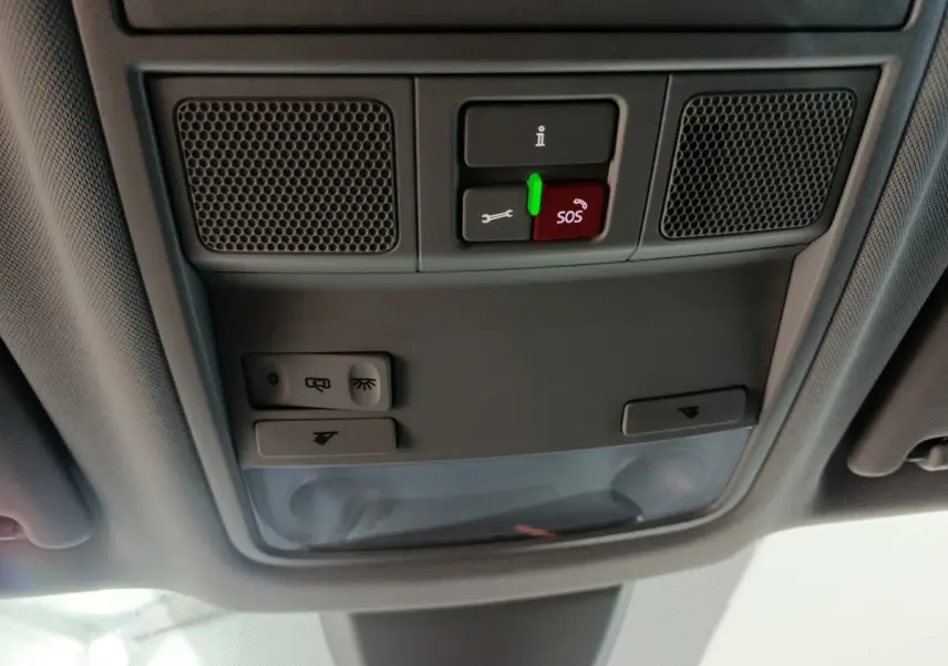 Vue en contre-plongée du plafonnier gris avec boutons SOS et commandes d'éclairage dans un Skoda Karoq blanc 2024.