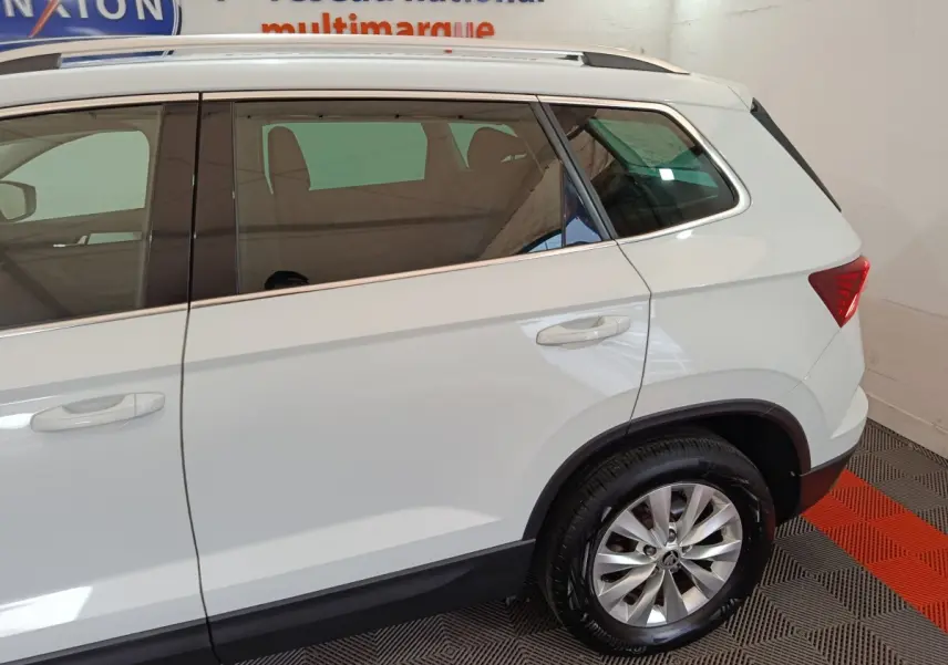 Vue latérale droite du Skoda Karoq blanc 2024, mettant en valeur les jantes alliage et les vitres teintées arrière.