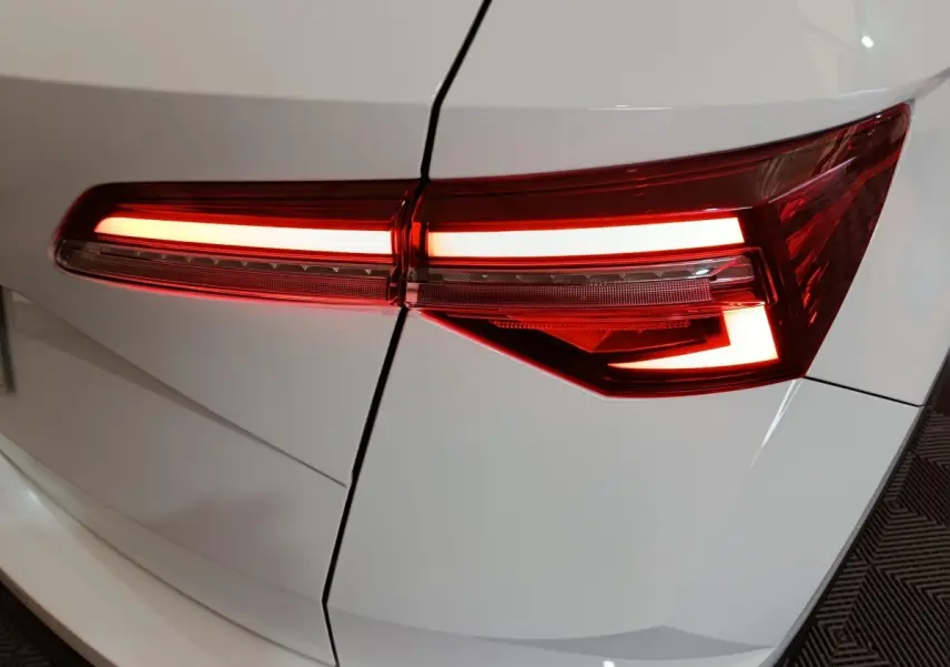 Gros plan sur le feu arrière droit allumé d’un Skoda Karoq blanc, soulignant les lignes nettes de la carrosserie.