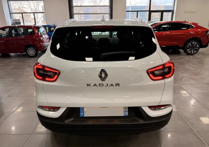 Vue arrière d'un Renault Kadjar blanc Glacier 2020 en intérieur, avec feux arrière allumés et logo central visible.