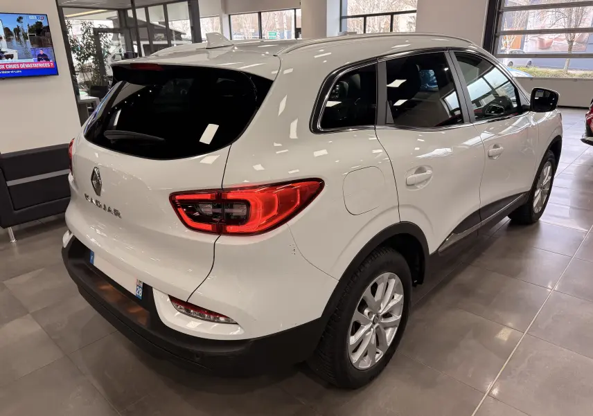 Vue 3/4 arrière droite d'un Renault Kadjar blanc Glacier 2020 en showroom avec feux arrière LED et jantes alliage.