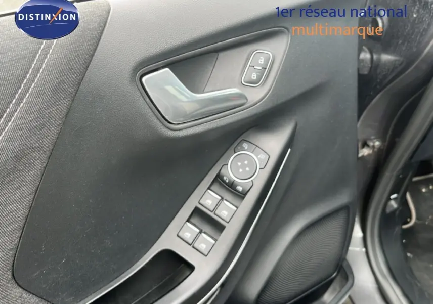 Gros plan sur la porte avant gauche du Ford Puma gris 2021, montrant les commandes électriques et la poignée intérieure.