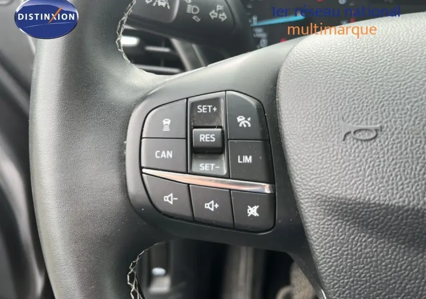 Gros plan sur les commandes au volant du Ford Puma gris 2021, mettant en valeur les boutons de régulateur et volume.