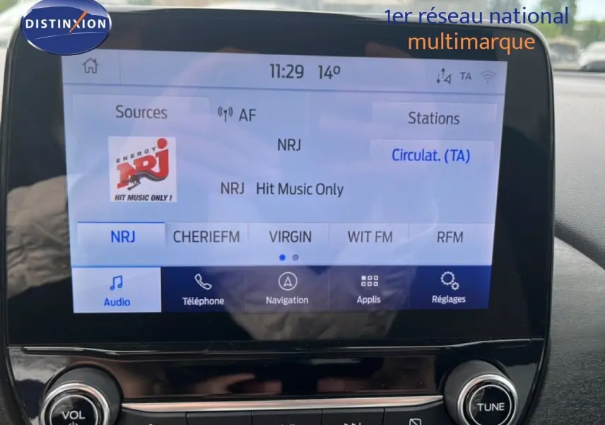 Vue intérieure du tableau de bord du Ford Puma gris 2021, écran tactile multimédia affichant une radio FM.