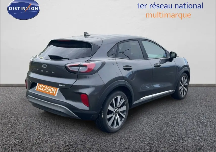 Ford Puma gris vue 3/4 arrière droit, SUV compact avec feux arrière distinctifs et jantes alliage.