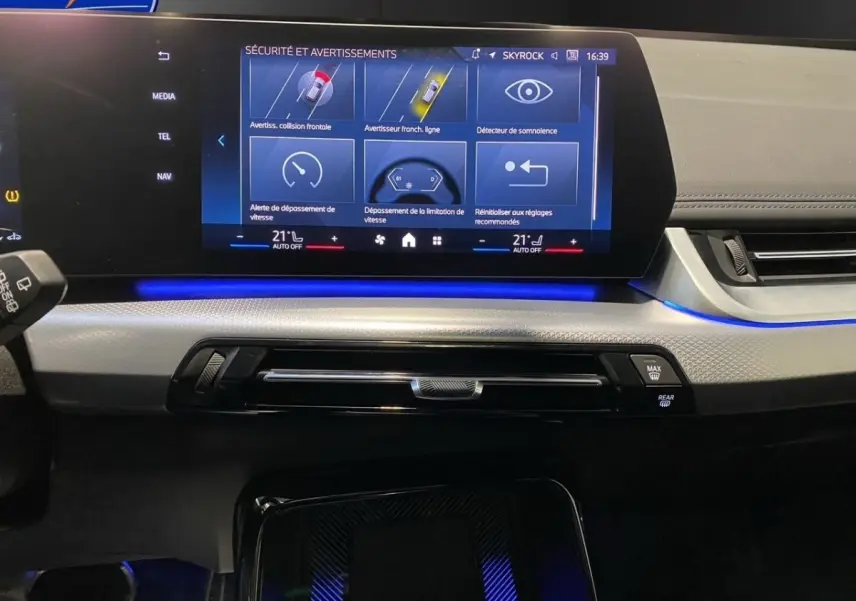 Vue rapprochée du tableau de bord et écran tactile central du BMW X1 noir 2025 avec éclairage d'ambiance bleu.