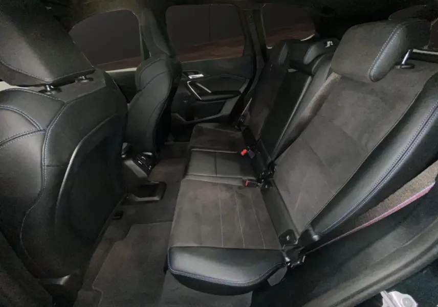 Vue intérieure arrière côté droit du BMW X1 2025 noir, sièges en cuir et alcantara avec surpiqûres bleues.
