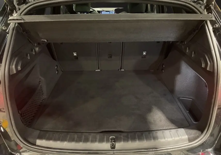 Coffre ouvert vu de l'arrière d'un BMW X1 noir, montrant un espace de chargement propre et spacieux.
