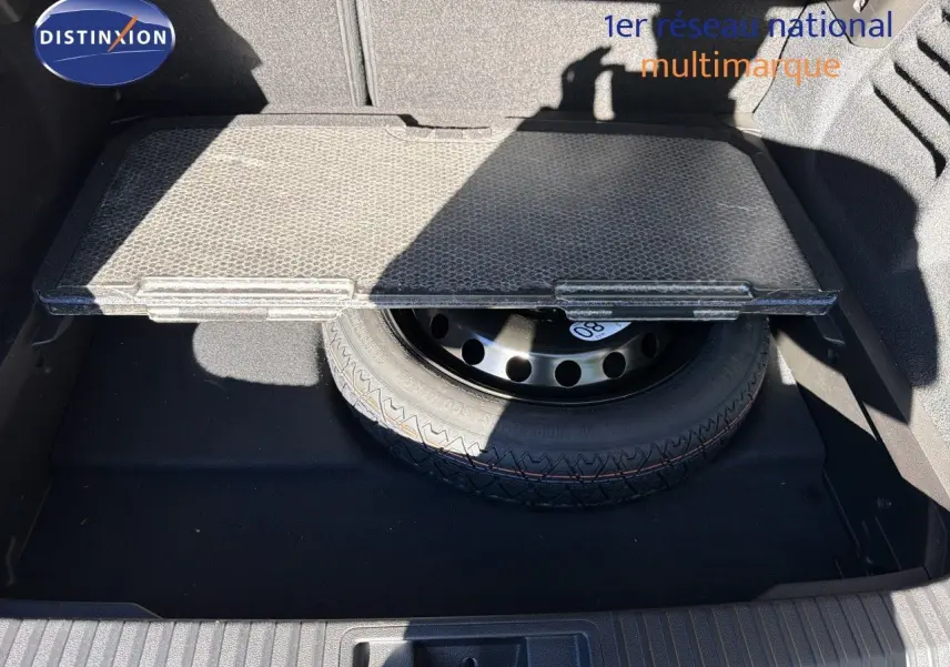 Vue plongeante sur le coffre ouvert du Renault Symbioz gris Rafale, montrant la roue de secours sous la tablette amovible.