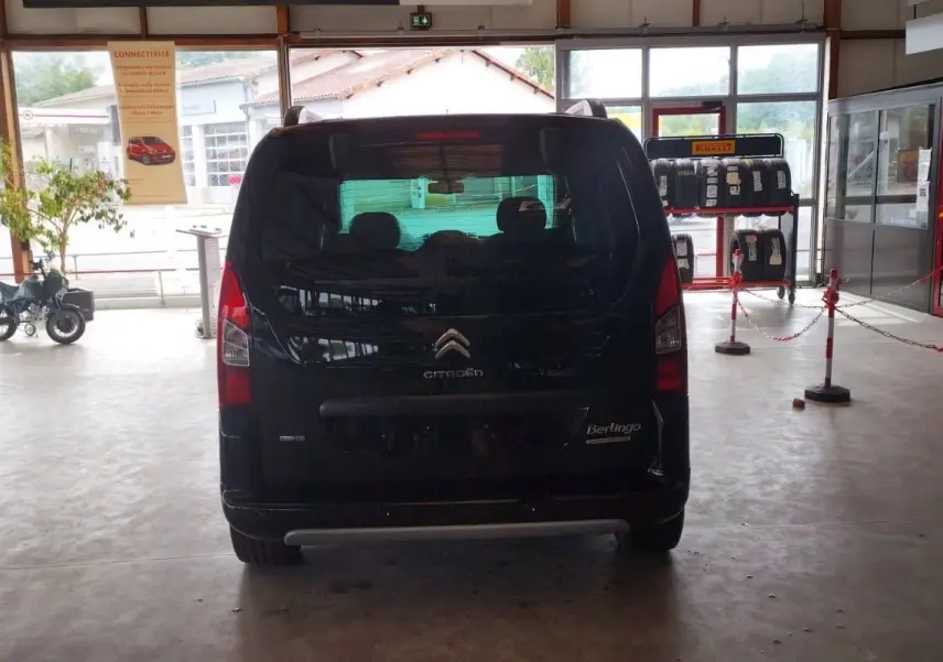 Vue arrière d'un Citroën Berlingo noir 2016 exposé en intérieur, avec vitres teintées et feux verticaux rouges.