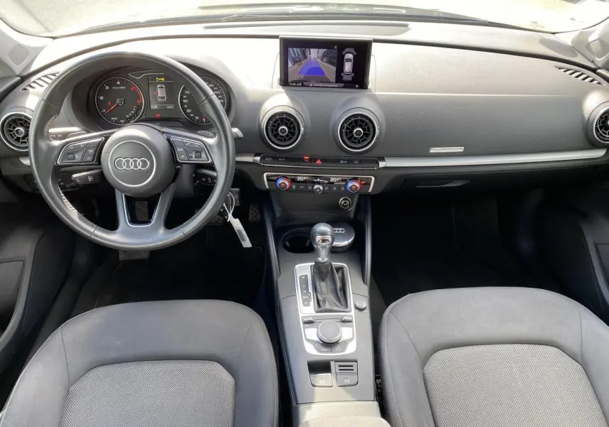 Vue intérieure avant de l'Audi A3 Sportback 2020, tableau de bord noir avec écran central et volant multifonction.
