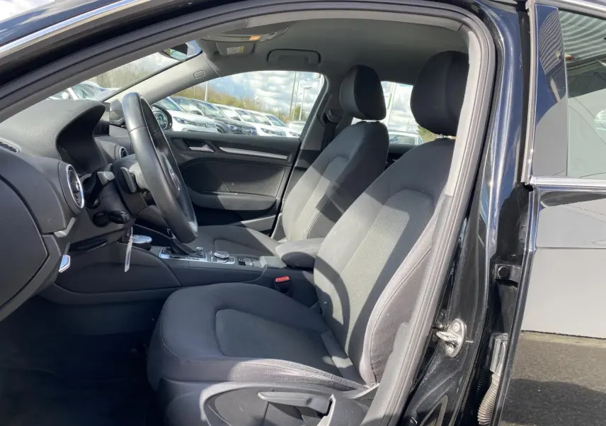 Vue intérieure côté conducteur de l'Audi A3 Sportback 2020 noir mythic metal, sièges tissu gris et console centrale visible.