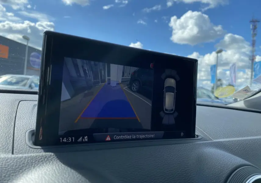 Écran central de l'Audi A3 Sportback 2020 montrant la caméra de recul et l'aide au stationnement en extérieur lumineux.