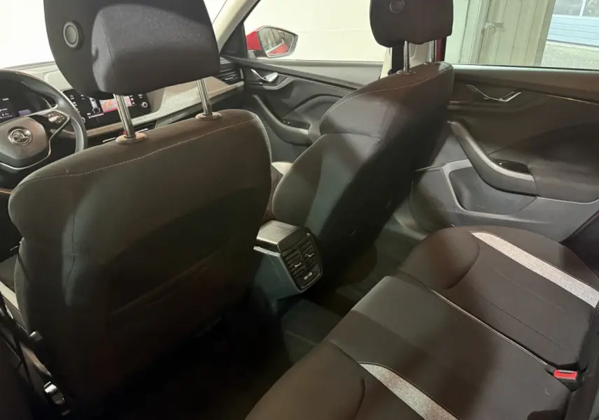 Vue intérieure arrière du Skoda Kamiq 2024 avec sièges noirs et console centrale avec aérateurs et ports USB.