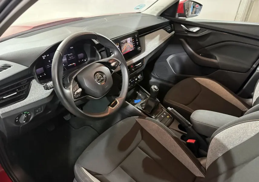 Vue intérieure côté conducteur du Skoda Kamiq 2024 rouge, volant cuir multifonctions et écran tactile central visible.
