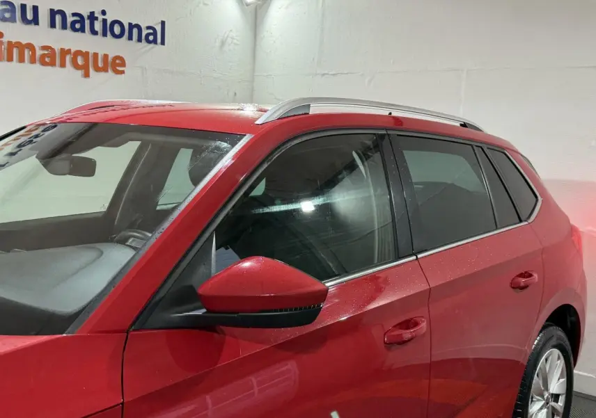 Vue latérale gauche du SUV SKODA KAMIQ rouge 2024, mettant en valeur la porte, le rétroviseur et les rails de toit argentés.