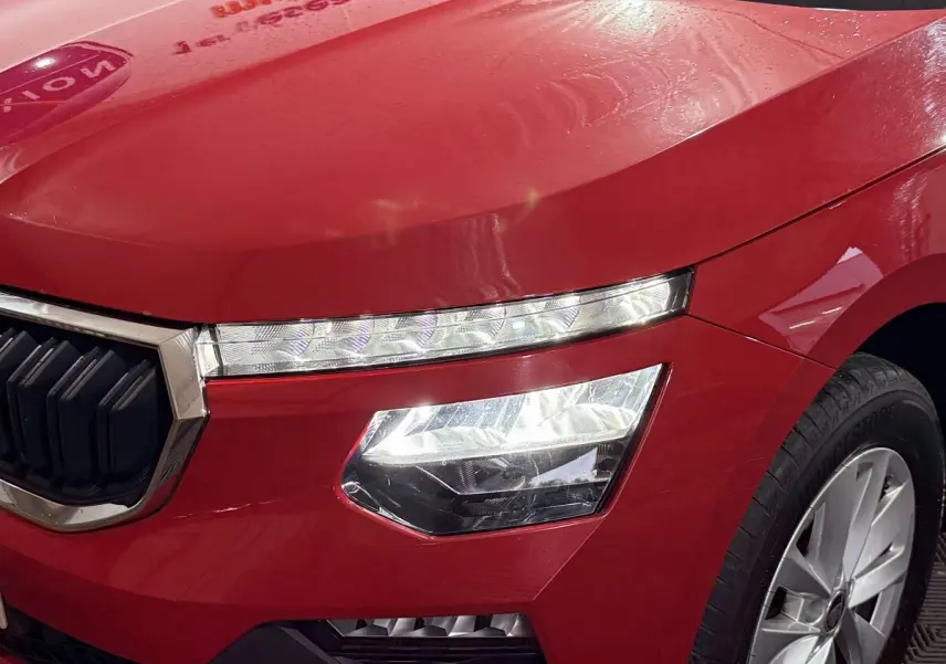Gros plan sur l’avant droit rouge vif du Skoda Kamiq 2024, mettant en valeur ses phares LED et la calandre chromée.