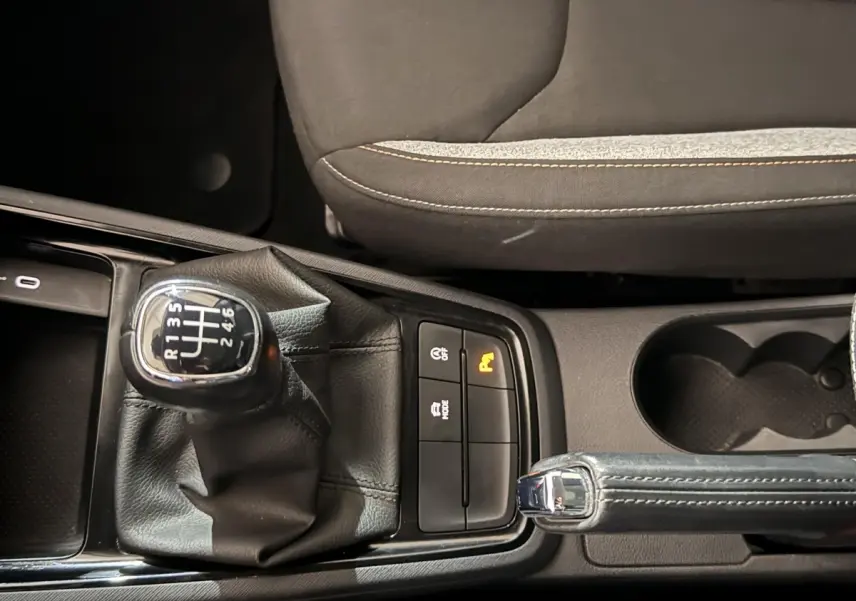 Gros plan sur levier de vitesses manuel et frein à main cuir dans l’habitacle d’un Skoda Kamiq rouge 2024.