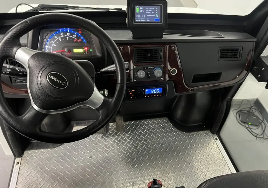 Vue intérieure de face du tableau de bord du Liberty L7E H2 160 blanc, volant 3 branches et revêtement sol aluminium.