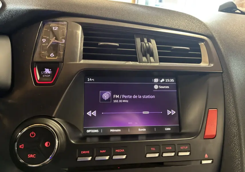 Vue rapprochée du tableau de bord gris du DS5 2018 avec écran tactile, horloge analogique et commandes rouges éclairées.