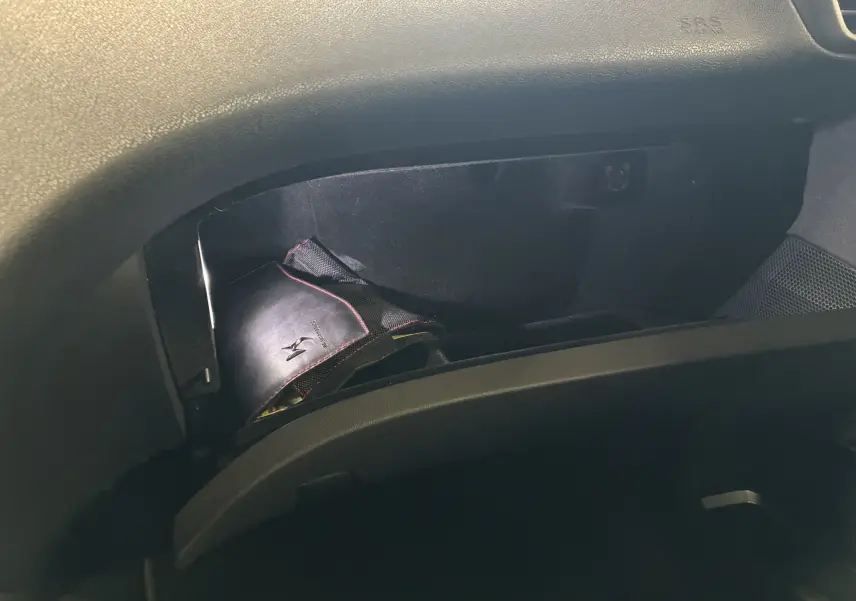 Vue intérieure du coffre à gants ouvert d'une DS5 gris, montrant un carnet de bord noir avec logo DS brodé.