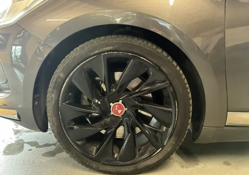 Gros plan sur la roue avant gauche noire à jante noire brillante du DS5 gris 2018, mettant en valeur le logo central rouge.