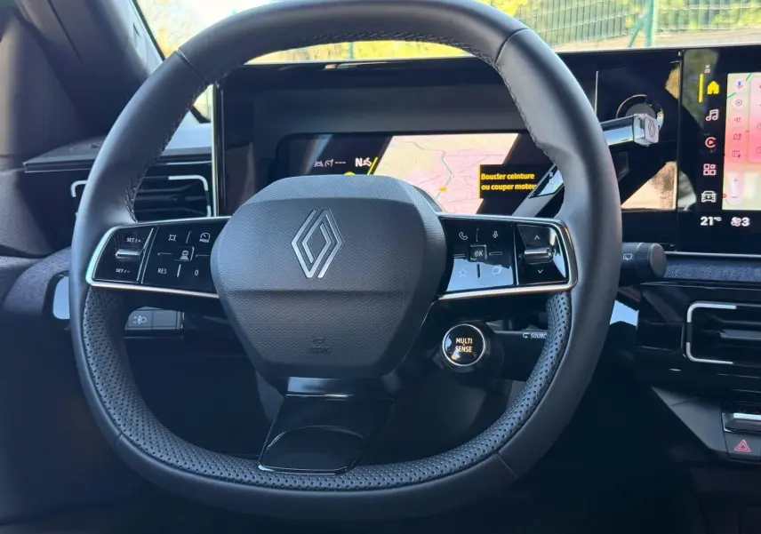 Vue rapprochée du volant noir perforé de la Renault R5 E-TECH 100% électrique avec tableau de bord numérique visible.