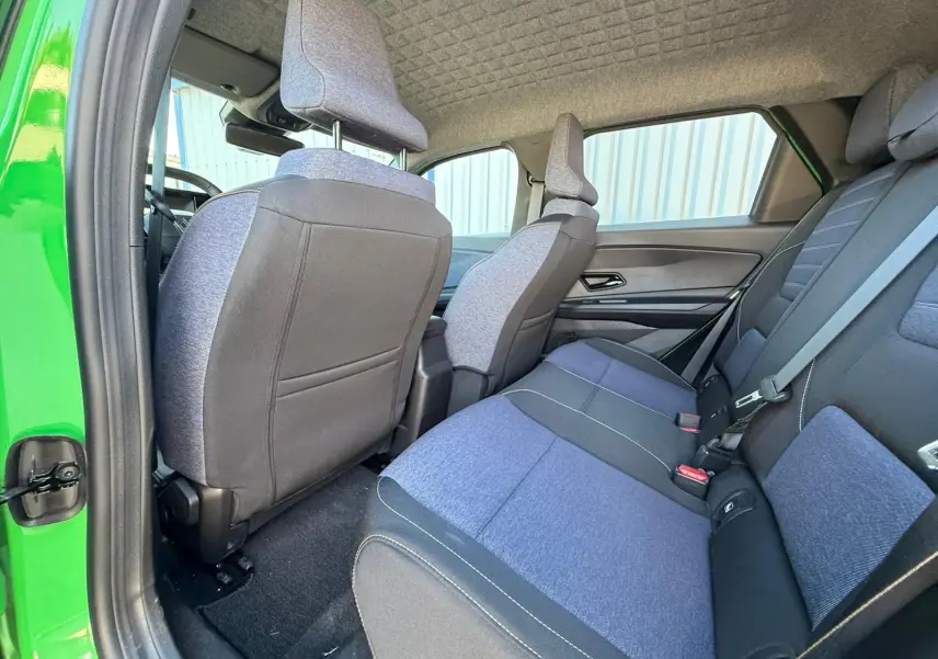 Vue intérieure arrière côté gauche de la Renault R5 E-TECH 100% électrique, sellerie textile bleu et noir, porte verte ouverte.