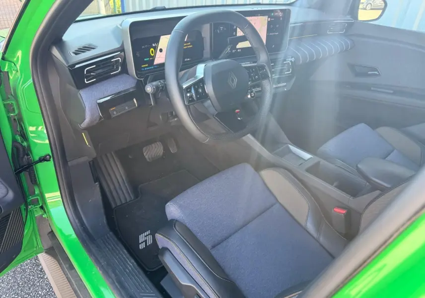 Vue intérieure côté conducteur de la Renault R5 E-TECH 100% électrique Vert Pop, avec sellerie textile bleu et tableau de bord numérique.