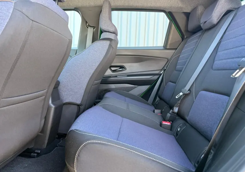 Vue latérale intérieure arrière de la Renault R5 E-TECH 2024, sièges en textile bleu et gris avec surpiqûres contrastantes.