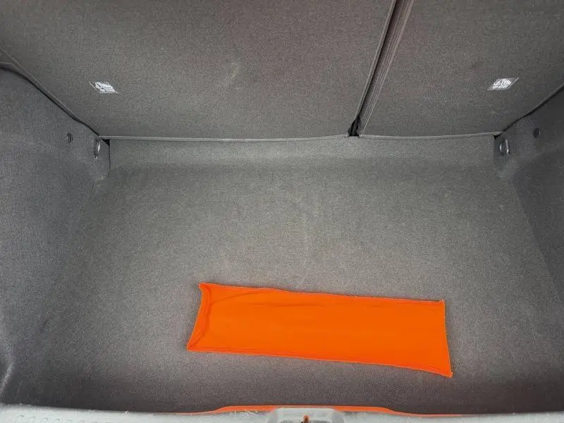 Vue intérieure du coffre noir de la Citroën C3 1.2 Turbo 100ch MAX avec un tapis orange au centre.