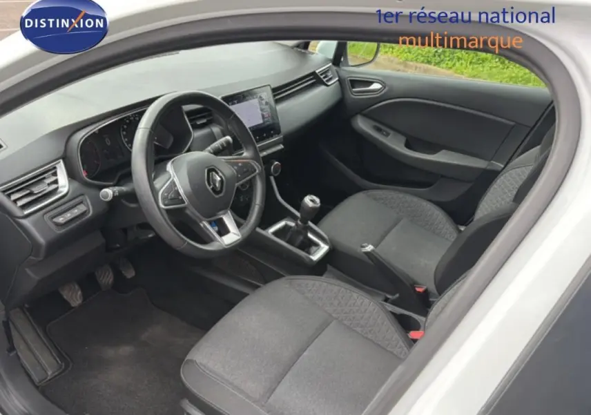 Vue intérieure côté conducteur de la Renault Clio blanche 2021, avec tableau de bord moderne et boîte manuelle.