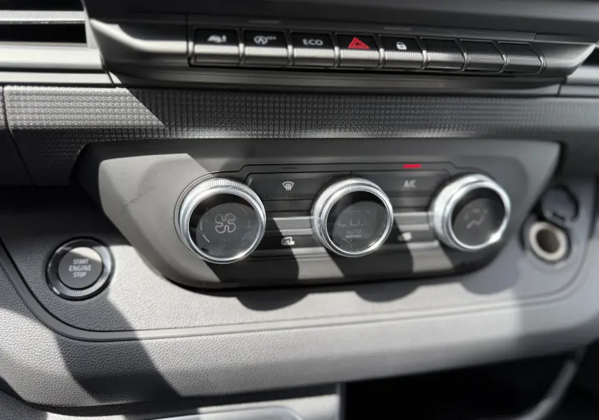 Gros plan sur la console centrale du Renault Trafic Fourgon blanc 2025, montrant les commandes de climatisation et le bouton Start Engine Stop.