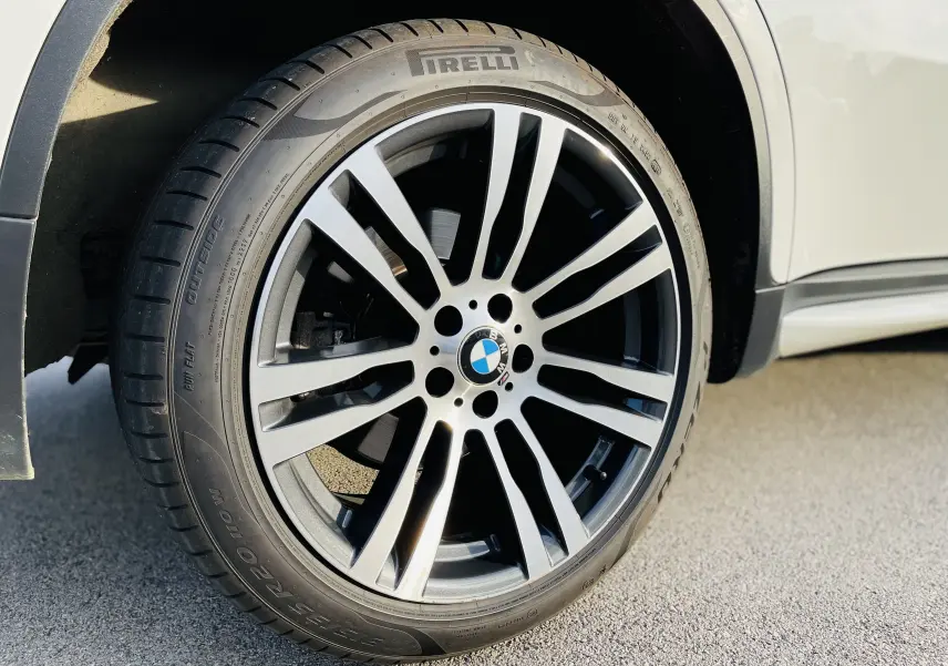 Gros plan sur la roue avant gauche du BMW X6 blanc, mettant en valeur la jante M sport et le pneu Pirelli.