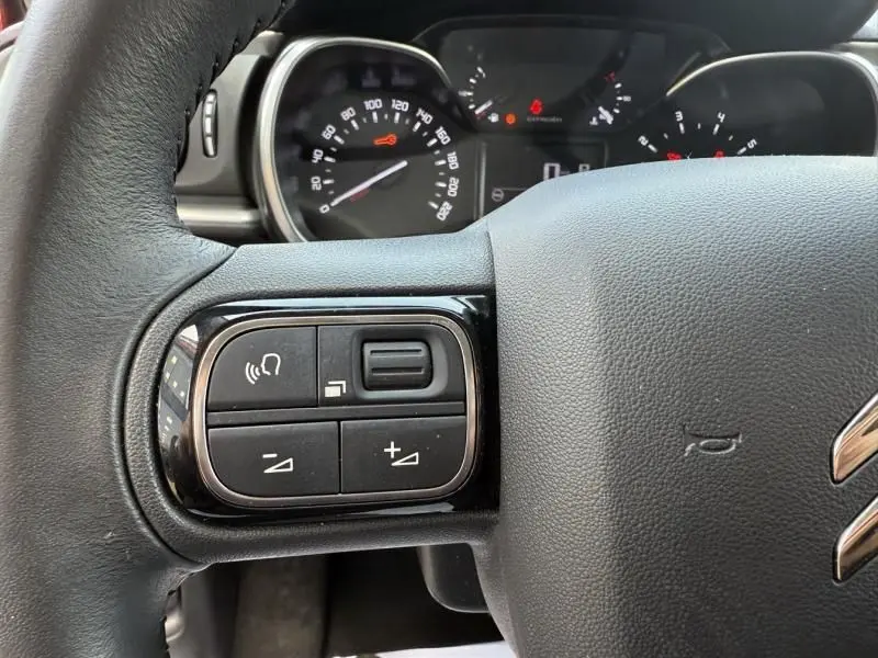 Gros plan sur les commandes au volant gauche et le tableau de bord digital d'une Citroën C3 noire toit blanc, version 2021.