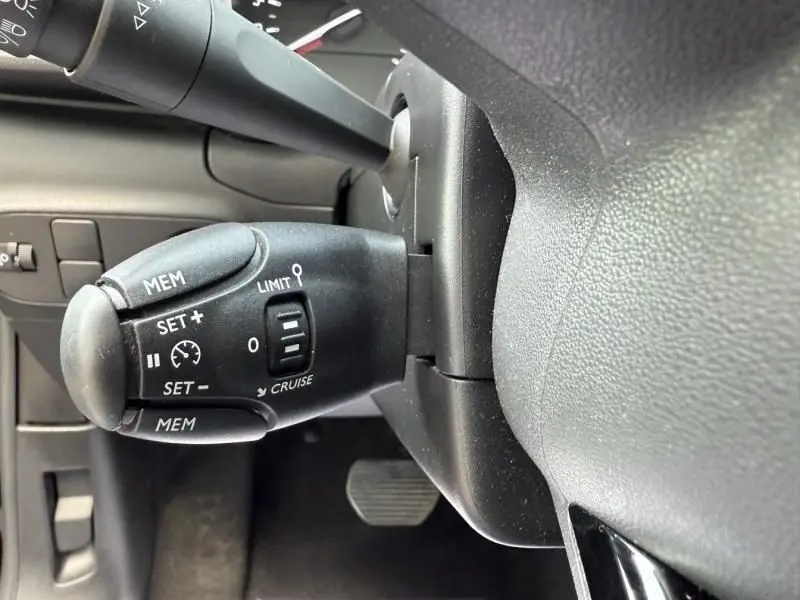 Gros plan sur la commande de régulateur de vitesse à gauche du volant dans une Citroën C3 2021 essence noir/toit blanc.