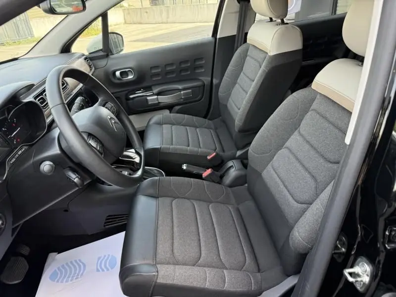 Intérieur avant droit de la Citroën C3 2021 noir avec toit blanc, sièges gris à appuie-têtes clairs et tableau de bord moderne.
