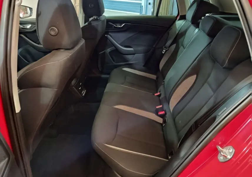 Vue intérieure côté droit sur la banquette arrière noire du Skoda Kamiq rouge 2024 avec portes ouvertes.