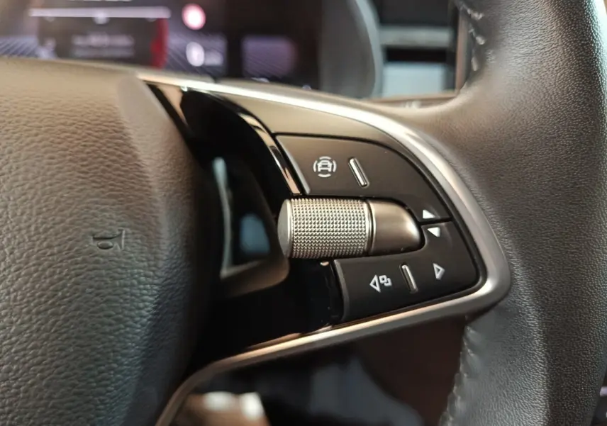 Gros plan sur le bouton multifonctions en métal du volant cuir noir du Skoda Kamiq 2024, côté gauche.