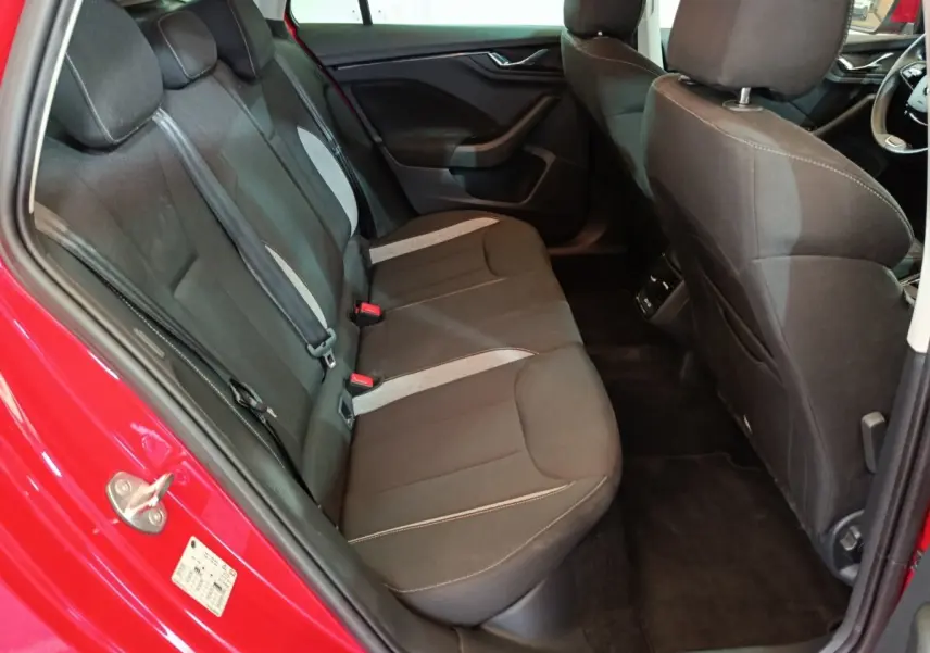 Vue intérieure côté arrière gauche du Skoda Kamiq rouge 2024, montrant la banquette tissu noire avec inserts gris.