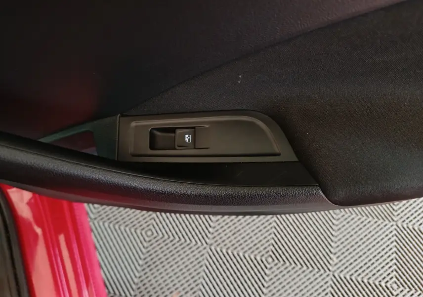 Gros plan sur le bouton de verrouillage des portes côté conducteur d’un Skoda Kamiq rouge 2024.